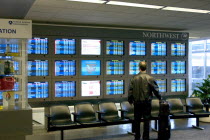 Traveller checking Northwest Airlines departure and arrival information screens at the Minneapolis-St. Paul International Airport Charles Lindbergh Terminal