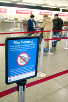 Northwest Airlines security ticket screener at Minneapolis-St. Paul International Airport Charles Lindbergh Terminal and sign warning not to send film through security equipment.