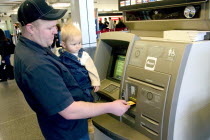 Father with baby son withdrawing cash at the ATM machine in the Minneapolis-St. Paul International Airport Charles Lindbergh Terminal.