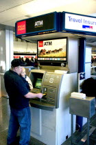 Father with baby son withdrawing cash at the ATM machine in the Minneapolis-St. Paul International Airport Charles Lindbergh Terminal.