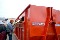 Recycling cardboard in a large orange dumpster at Vasko Disposal Solutions.