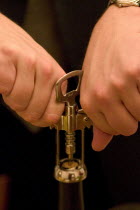 Opening a bottle of wine with a corkscrew.