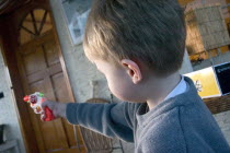 Boy aged 4 aiming colorful toy cap gun.