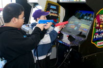 Kids aged 11 shooting Point Blank video game with red and blue replica 45 caliber plastic pistols.