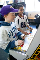 Friends age 10 playing video games developing their eye hand coordination at the Youth Express inner city activity centerCentre