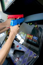 Teenagers shooting Point Blank video game with red and blue replica 45 caliber plastic pistols.