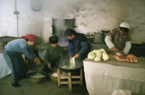 Preparing and cooking meat and vegetables in kitchen of comune.