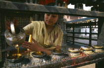 Young girl filling butterwick candles in shrine dedicated to Hariti  known today as Ajima in ancient temple on the outskirts of Kathmandu.UNESCO World Heritage SiteMonkey Temple Swayambhunath