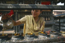 Young girl filling butterwick candles in shrine dedicated to Hariti  known today as Ajima in ancient temple on the outskirts of Kathmandu.UNESCO World Heritage SiteMonkey Temple Swayambhunath