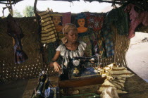 Dressmaker using an old Singer sewing machine in her workshop surrounded by fabrics