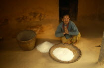 Elderly woman with woven basket of grains.