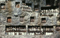 Toraja wooden funeral effigies or tau tau in cliff graves.  The figures accompany the dead from funeral house to burial ground and watch over both the living and dead.