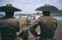 Charros or cowboys watching horseman in local rodeo.Rider