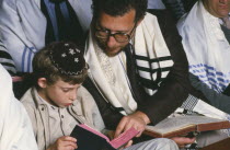 Jewish father and son attending preparation for Bar Mitzwah in synagogue.