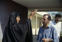 Marsh Arab woman talking and demonstrating with a hand gesture to a Oxfam engineer.school teacher