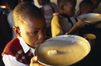 Boy drinking from bowl of breakfast at the Kititimo Centre School for street children.
