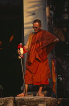 Buddhist monk wearing sunglasses and carrying an elaborate walking stick watching the Shaman ceremonyAsian Cambodian Kampuchea Religion Southeast Asia Kamphuchea Religion Religious Buddhism Buddhists
