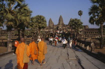Buddhist monks and tourists during Chinese New Year on tree lined stone causeway leading to temple complex.Asian Cambodian Kampuchea Religion Southeast Asia History Holidaymakers Kamphuchea Religion...