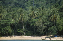 Koh Rok with a man beside a fishing boat on the shoreline below the tree lined hill