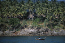 The Narima Spa Resort chalets amongst coconut palm trees with a man on a small fishing boat offshoreAsian Prathet Thai Raja Anachakra Thai Siam Southeast Asia Male Men Guy Scenic Siamese Male Man Guy