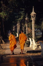 Two monks walking along the path lined with stone lanterns through the trees by the river Asian Cambodian Kampuchea Religion Southeast Asia 2 Kamphuchea Religious