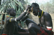 Karamojong warrior having beaded head dress fixed by a friend.  Great pride is taken in appearance.Pastoral tribe of the Plains Nilotes group related to the Masi