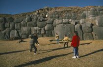 Local children playing volleyball in front of walls of Inca fort on Sunday. Cuzco