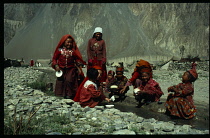 Group of Kirghiz children washing bowls in stream.
