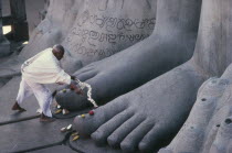 Jain puja at feet of seventeen metre high naked statue of Bahubali  the Gomateshvara.  One of the oldest and most important Jain pilgrimage centres in India.  Shravan Belgola