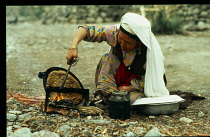 Kirghiz woman baking bread on outside fire.Nomadic people of paleo-Siberian origin