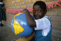 Schoolgirl with papier mache globe teaching aid made by PAMET who recycle everything from newspapers to elephant dung