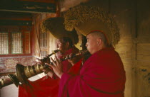 Yellow hat Buddhist Monks playing horn instruments in the temple Monastery of Lamas