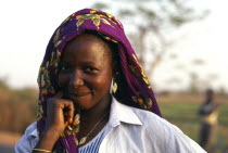 Portrait of smiling lady wearing purple headscarfe. Working in Paddy field.