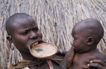 Surma woman with lip plate holding baby.