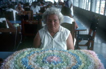 Female inmate sitting at a table in front of floral design