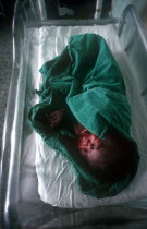 Newborn baby wrapped in green towel in maternity hospital