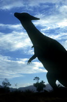 Life size dinosaur silhouetted in amusement park