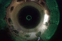 Inside a tunnel under construction with workers in the distance in a pool of light