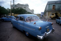 Old blue American cars being driven in the street
