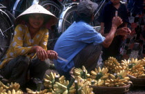 Woman selling bananas from woven baskets.
