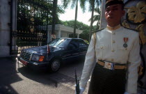 The Kings Palace.  Guard in uniform outside palace gates with official car about to drive through.