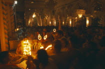 Dirwali festival  crowds of worshippers holding lighted candles in dark temple interior.