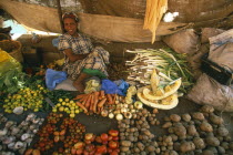 Market outside the city walls.  Female vendor sitting behind display of vegetables laid out on the ground in front of her.