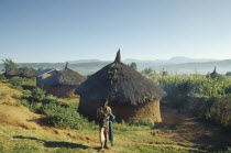 Village near city of Harer.  Circular  thatched huts with villager holding a baby standing in the foreground.