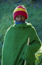 Portrait of young man wrapped in green woven blanket.