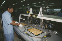 Man working in a factory producing circuit boards.