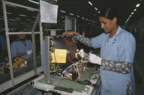 Woman in factory making electrical components for televisions.