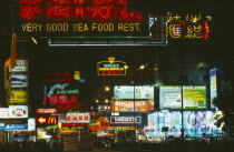 Busy street with neon signs and advertising illuminated at night.
