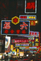 Busy street with neon signs and advertising illuminated at night and traffic with streaked light trails.