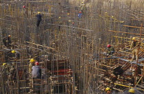 Construction workers on scaffolding amongst steel fixing on a building site.